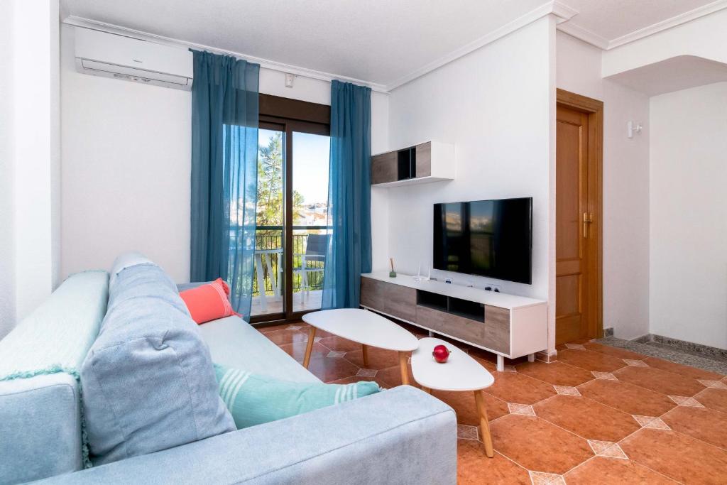 a living room with a blue couch and a tv at Espanatour PLAYA FLAMENCA in Orihuela Costa