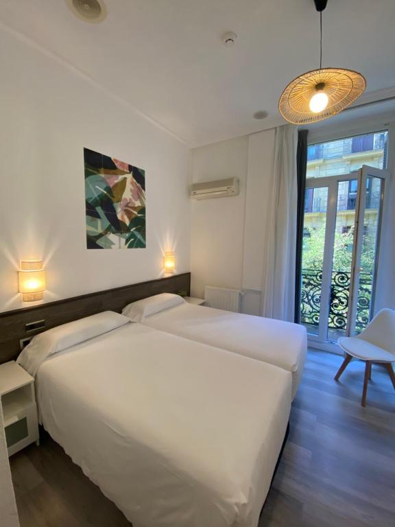 a bedroom with two white beds and a window at Pensión Donostiarra in San Sebastián