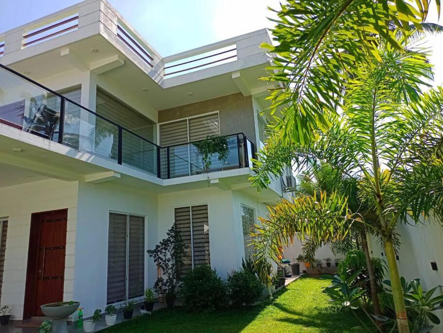 a white house with a balcony and a yard at Kurulu Villa Hikkaduwa in Gonapinuwala West