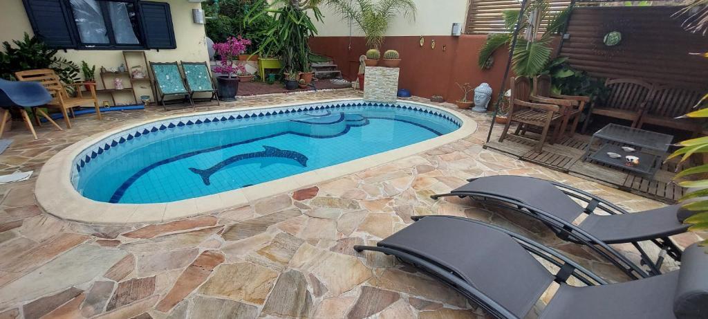 uma piscina com duas cadeiras num quintal em Nidamour, un logement fait pour vous em Saint-Paul