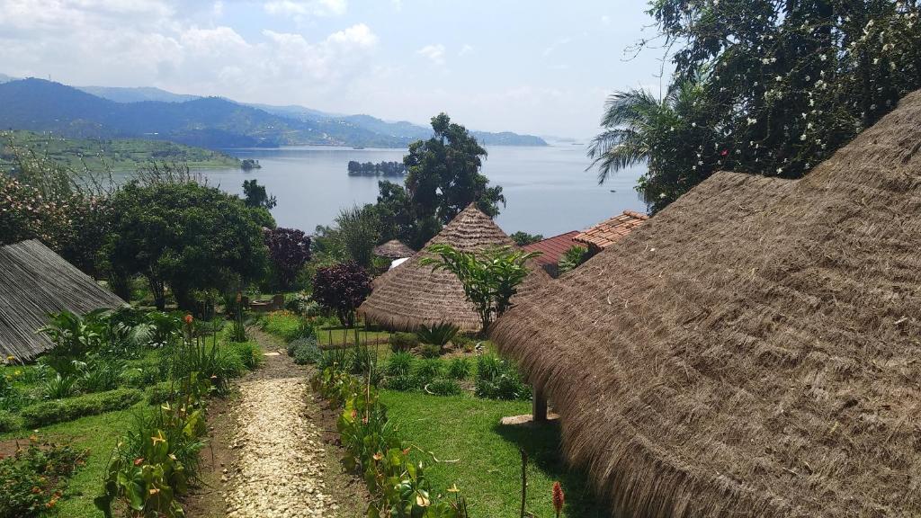 a group of straw huts with a view of a lake at INZU Lodge in Gisenyi