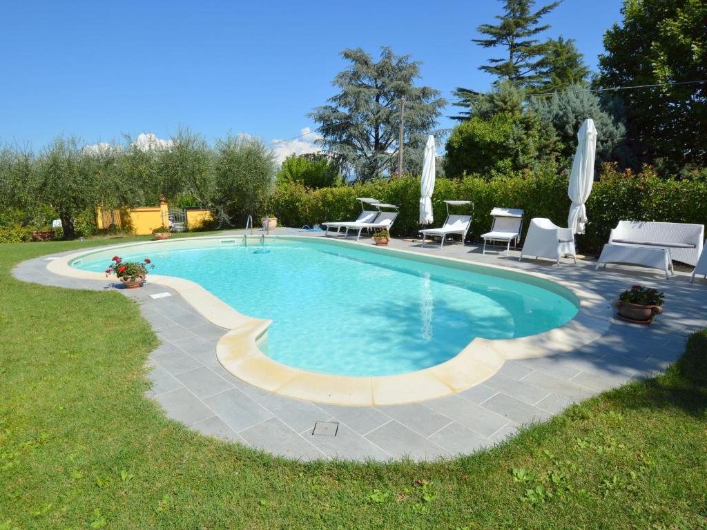 een zwembad in een tuin met stoelen en tafels bij Attractive villa in Marsciano Perugia with a pool in Marsciano