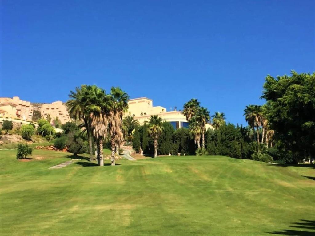 a golf course with palm trees and a building at Amazing apartment in La Env a with private terrace in La Envia