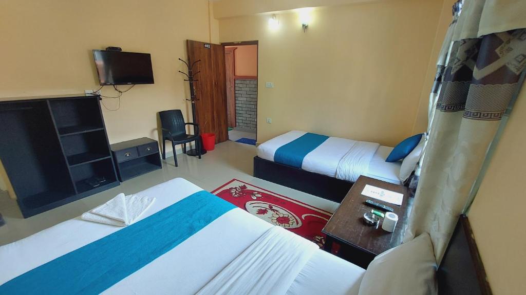 una camera d'albergo con due letti e una televisione di Golden Lake a Pokhara
