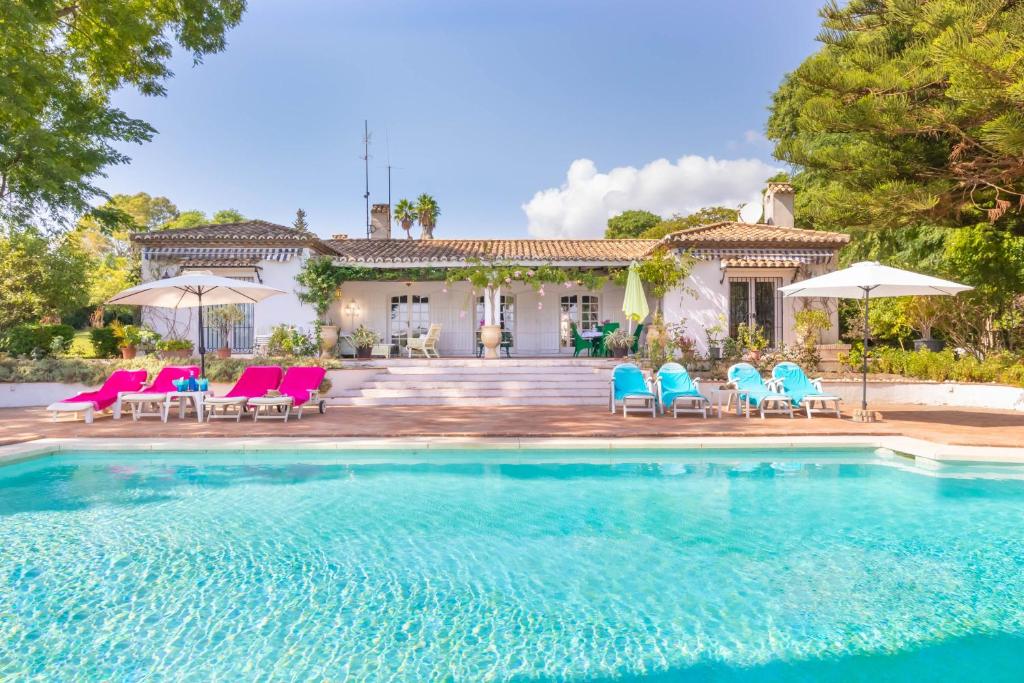 uma casa com piscina com cadeiras e guarda-sóis em Cortijo Villa Padierna El Lago - Happy Rentals em Estepona