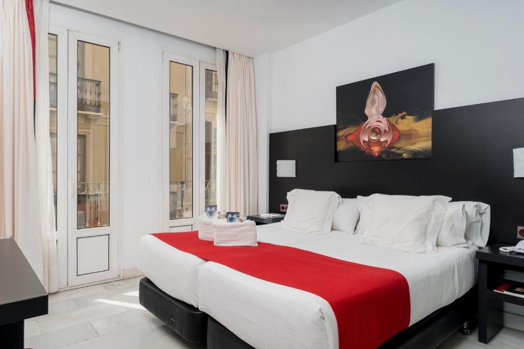 um quarto com uma cama grande e um cobertor vermelho em Hotel Del Pintor em Málaga