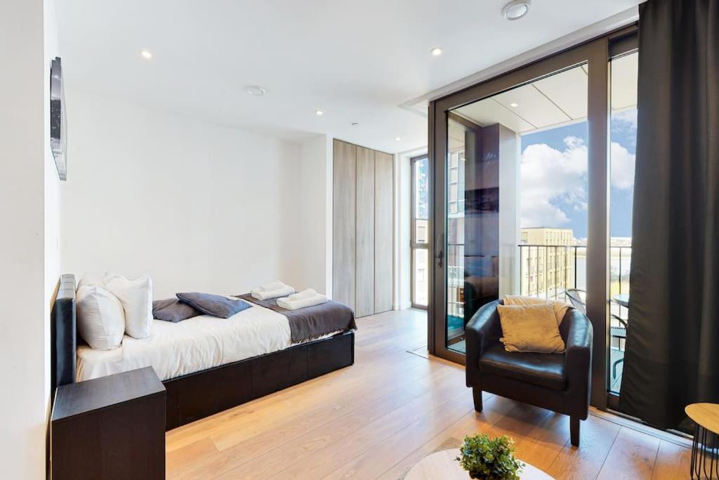 a bedroom with a bed and a chair and a balcony at Superb Studio in Greenwich with balcony & roof top in London