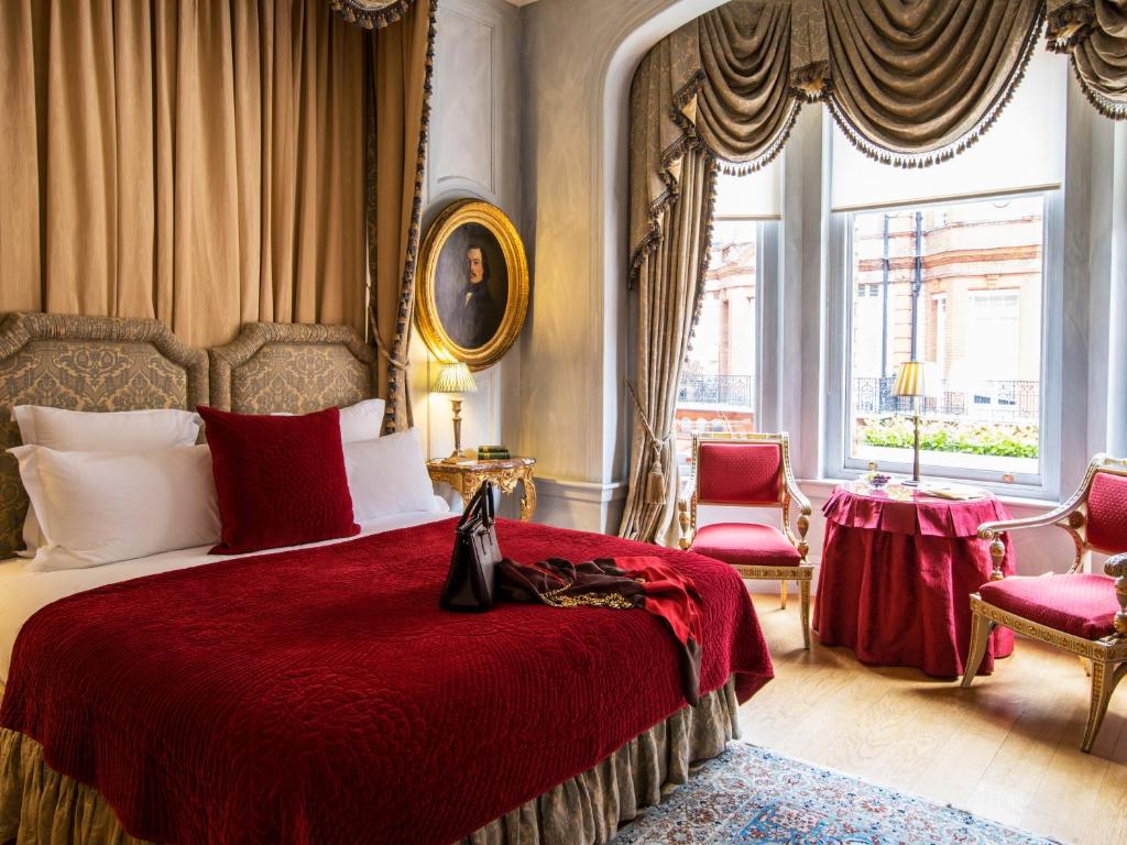 een slaapkamer met een bed met een rode deken en 2 stoelen bij San Domenico House in Londen