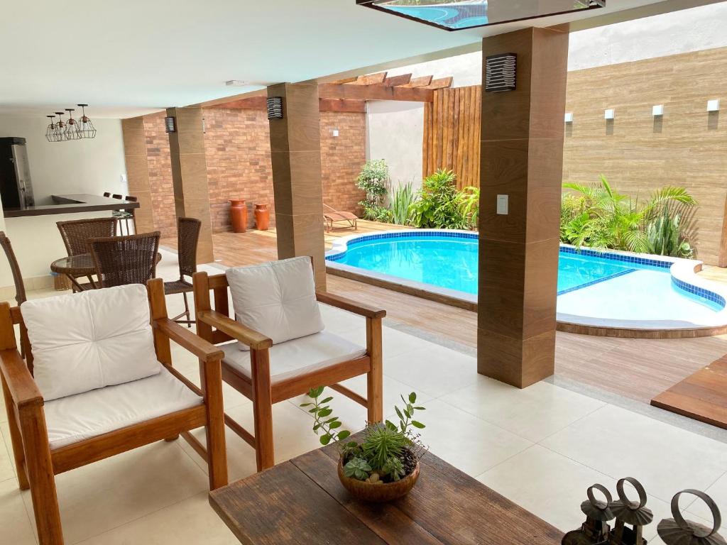 sala de estar con piscina, sillas y mesa en Hotel Portal do Descobrimento, en Porto Seguro