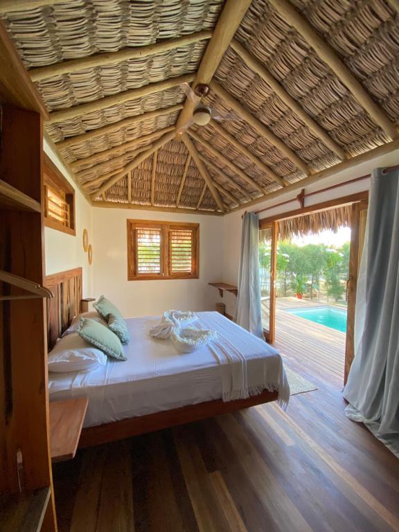 a bedroom with a bed and a wooden floor at Tiki Pool's Bungalows in Fortim