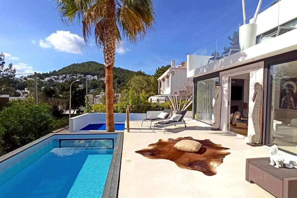 a house with a swimming pool next to a palm tree at Balinese Villa near the beach outdoor jacuzzi in Cala Llonga