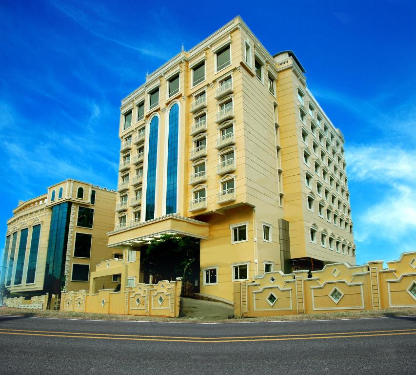 a tall building with blue windows on a street at Shenbaga Hotel And Convention Centre in Pondicherry