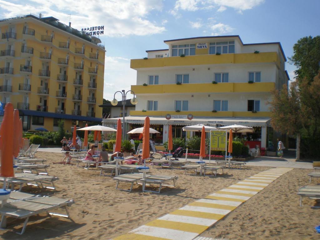 una playa con sillas y sombrillas y un edificio en Hotel Silva Frontemare, en Lido di Jesolo