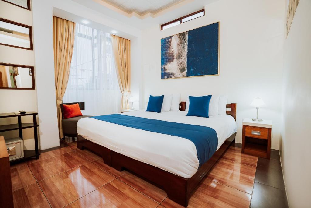 1 dormitorio con 1 cama grande con sábanas azules y blancas en Hotel Palace Galapagos, en Puerto Ayora