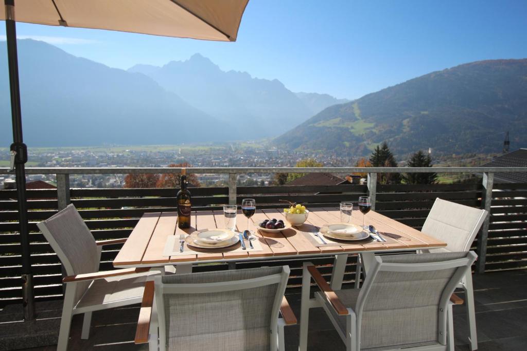 una mesa de madera con sillas y una sombrilla en el balcón en Sun Apartments - with Dolomiten Panorama en Lienz