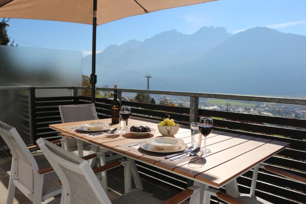 einen Holztisch mit Gläsern Wein auf dem Balkon in der Unterkunft Sun Apartments - with Dolomiten Panorama in Lienz