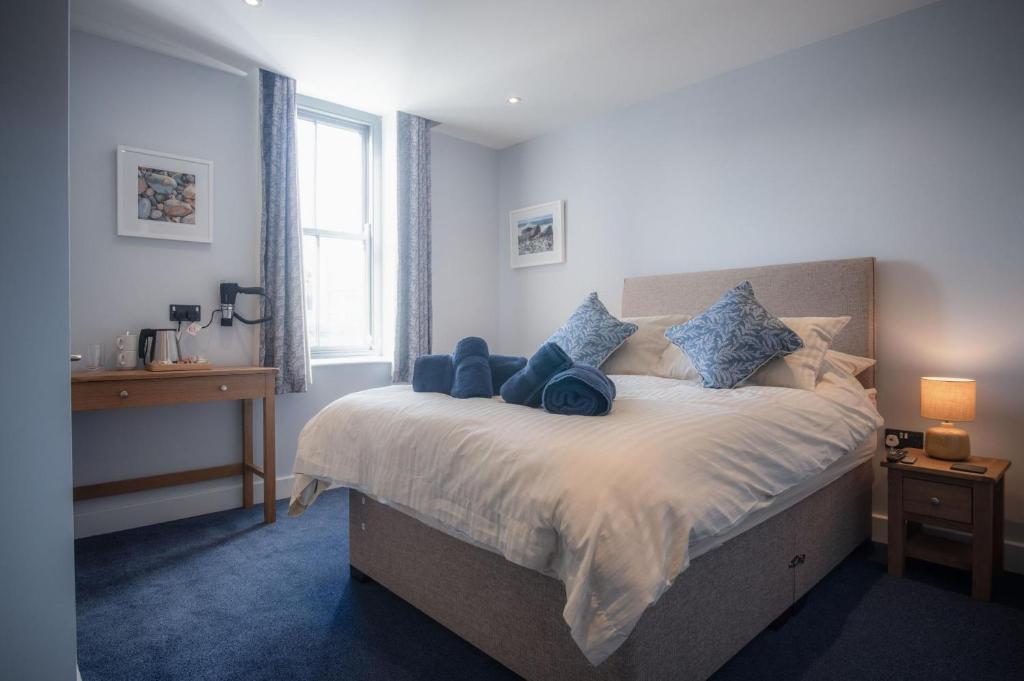 1 dormitorio con 1 cama grande con almohadas azules en Ocean Cabins No 5 At The Square - Saundersfoot en Saundersfoot