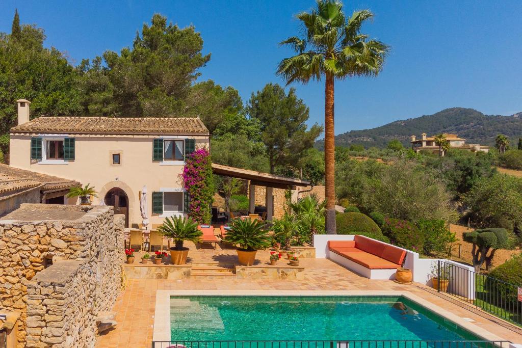 a house with a swimming pool and a palm tree at Finca Vallaca in Calonge