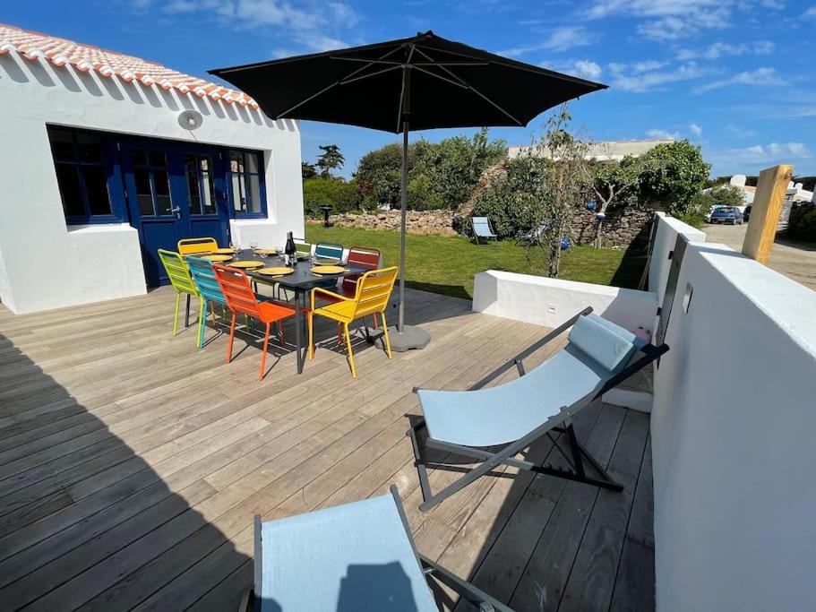 un patio avec une table, des chaises et un parasol dans l'établissement Charmante petite maison avec jardin plage des vieilles, à La Croix