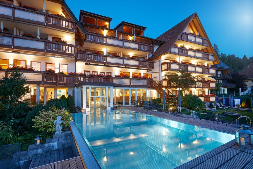 um grande edifício com uma piscina em frente em Erfurths Bergfried Ferien & Wellnesshotel em Hinterzarten