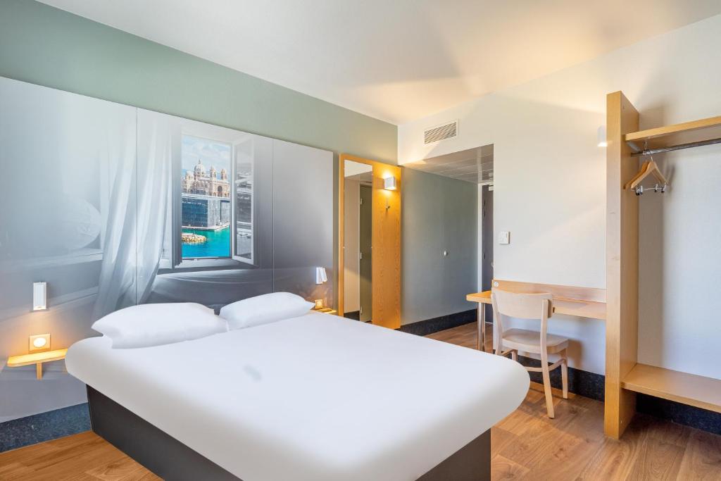 a bedroom with a large white bed and a table at B&B HOTEL Marseille Euromed in Marseille