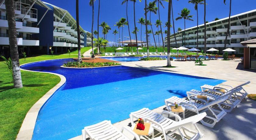 a swimming pool with lounge chairs and a resort at Ancorar flat resort paradise in Porto De Galinhas