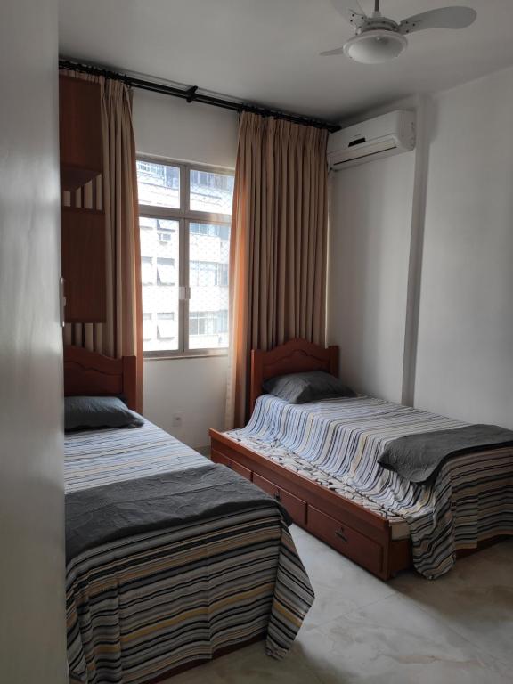 two beds in a room with a window at Seu Lugar Em Copacabana in Rio de Janeiro