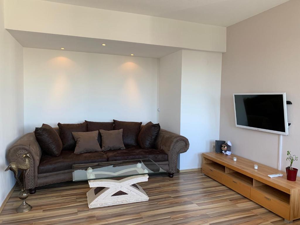a living room with a brown couch and a tv at Apartment Rebe in Schweinfurt