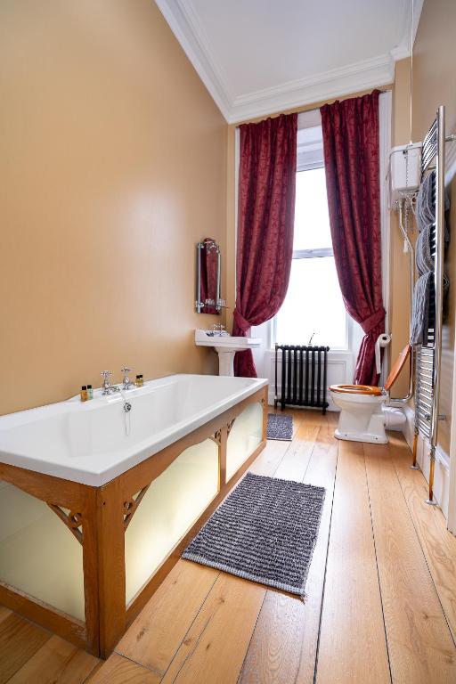 a bathroom with a large tub and a toilet at Antrim House Guest Rooms & Suites in Portrush