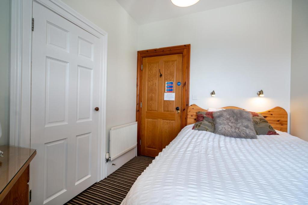a bedroom with a white bed and a wooden door at Antrim House Guest Rooms & Suites in Portrush