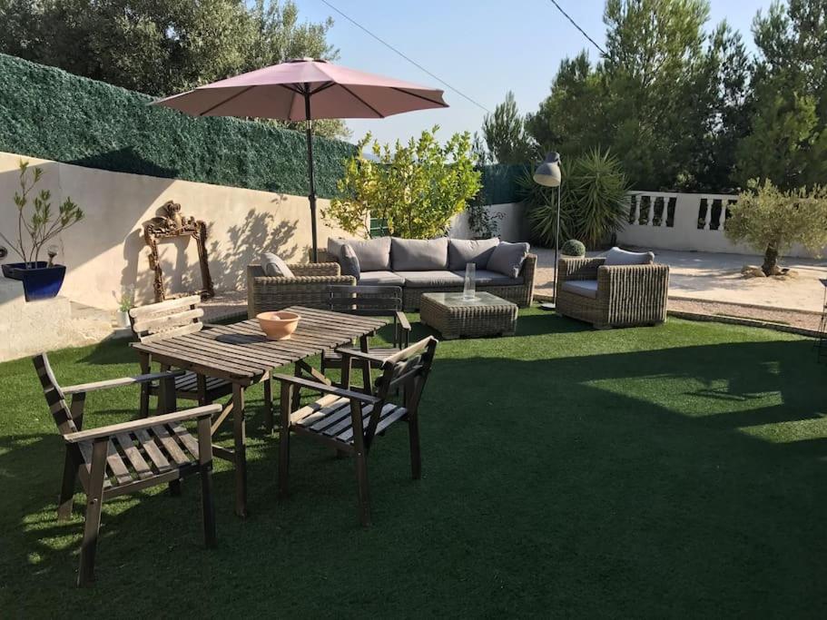 un patio avec une table, des chaises et un parasol dans l'établissement La Maison des Délices, au Beausset