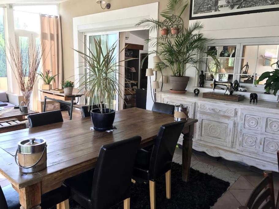 a dining room with a wooden table and plants at La Maison des Délices in Le Beausset