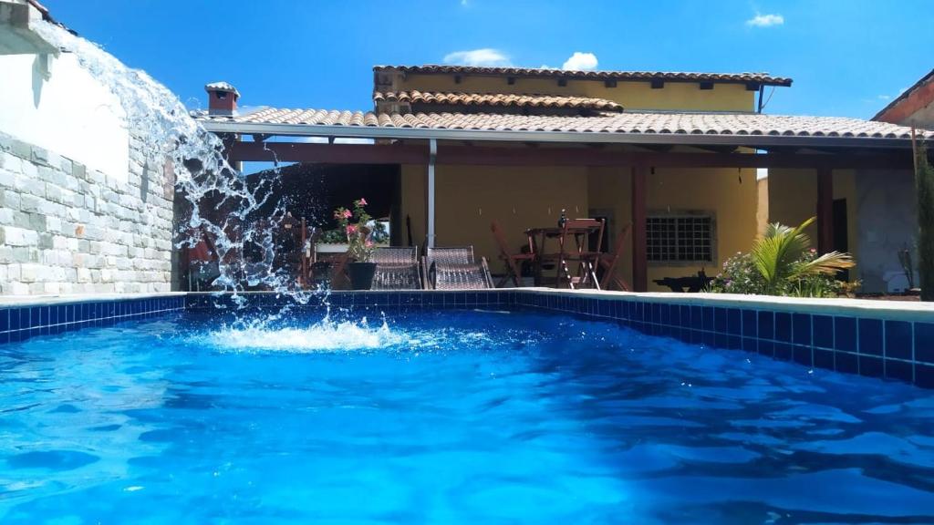 a swimming pool with a water fountain in front of a house at Casa Pirineus in Pirenópolis