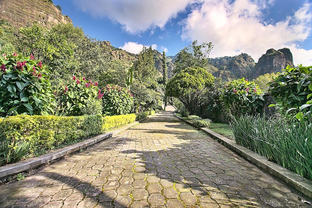 un camino empedrado en un jardín con montañas al fondo en Casa Jacobina Tepoztlán en Tepoztlán