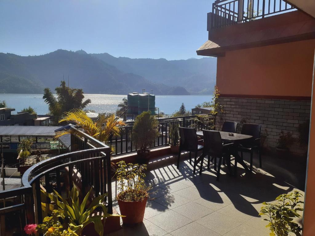 einen Balkon mit einem Tisch und Stühlen sowie Blick auf das Wasser in der Unterkunft Golden Lake in Pokhara