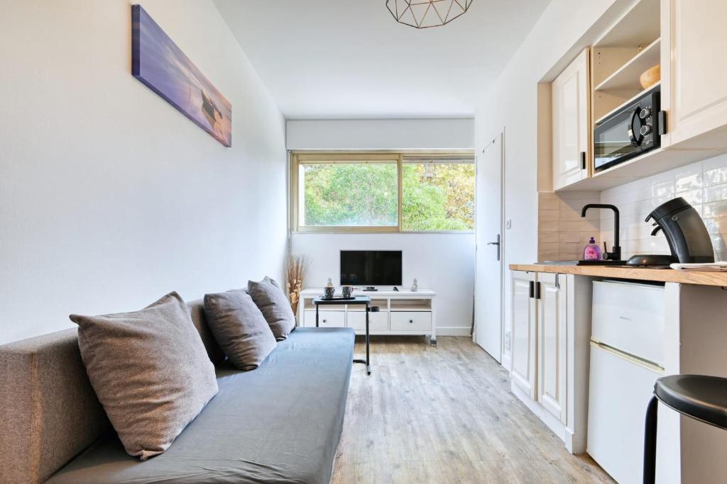 uma sala de estar com um sofá e uma cozinha em Paradis Prado furnished apartment em Marselha