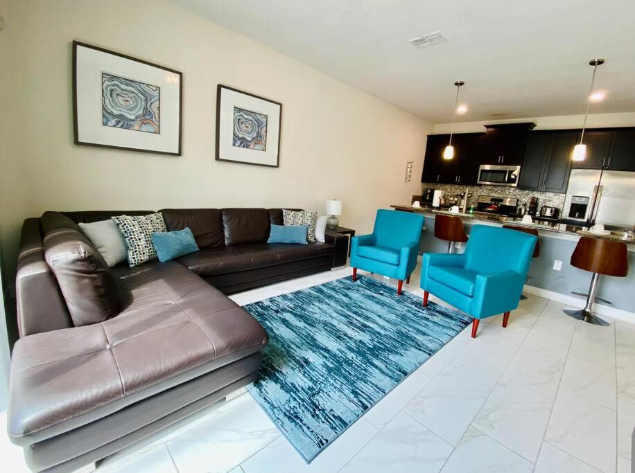 a living room with a leather couch and blue chairs at Excellent Resort Free/ Makin Memories / 4 Beds in Kissimmee