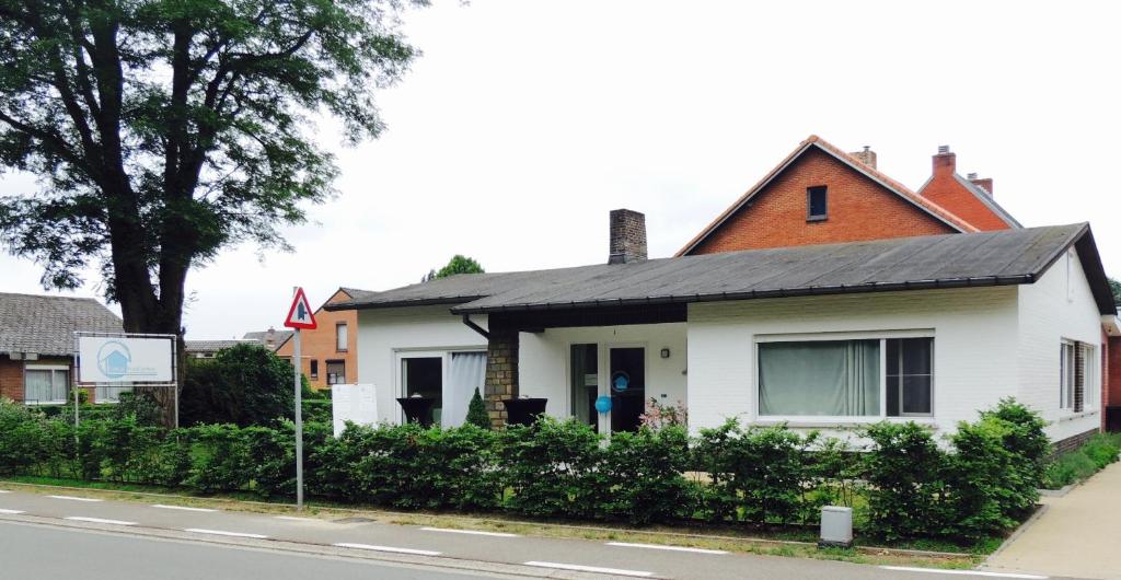 a white house with a black roof on a street at Fokus PraktijkHuis in Dessel