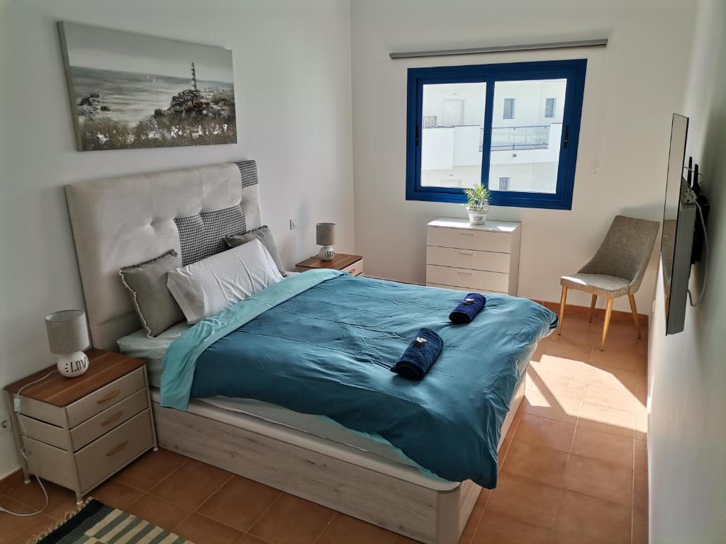Costa Calma Sun & Pool Apartment في كوستا كالما: غرفة نوم بسرير كبير مع لحاف ازرق