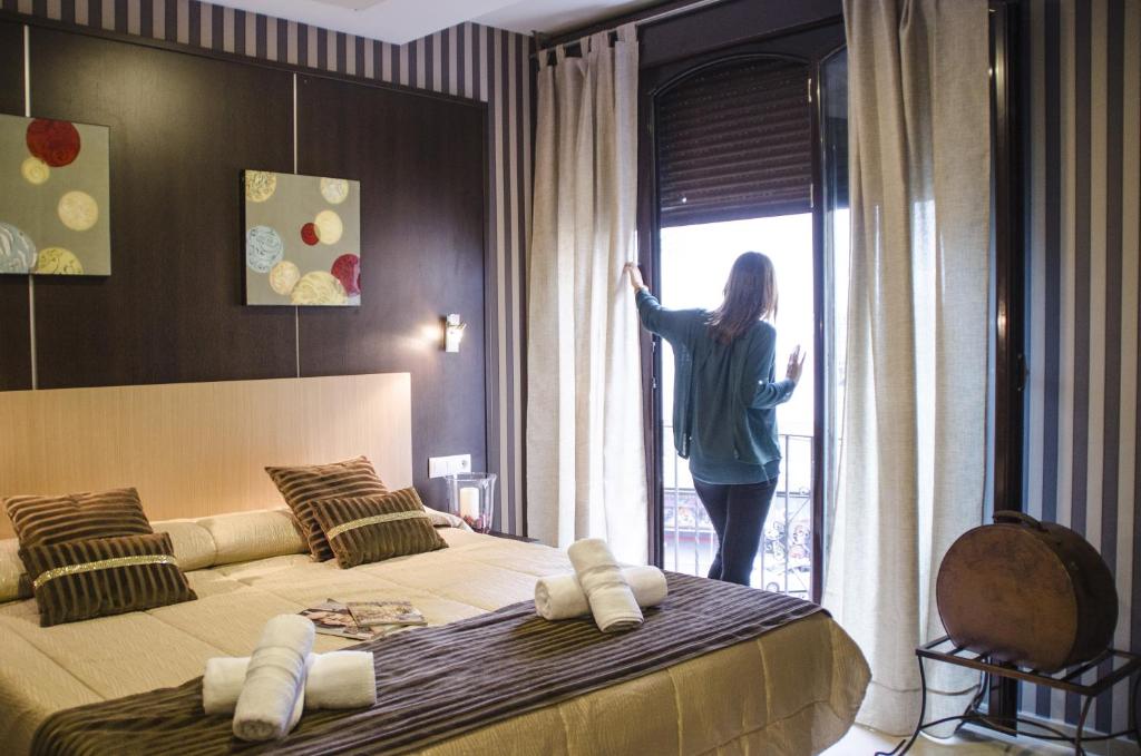 a woman looking out the window of a bedroom at Hotel Duquesa in Seville
