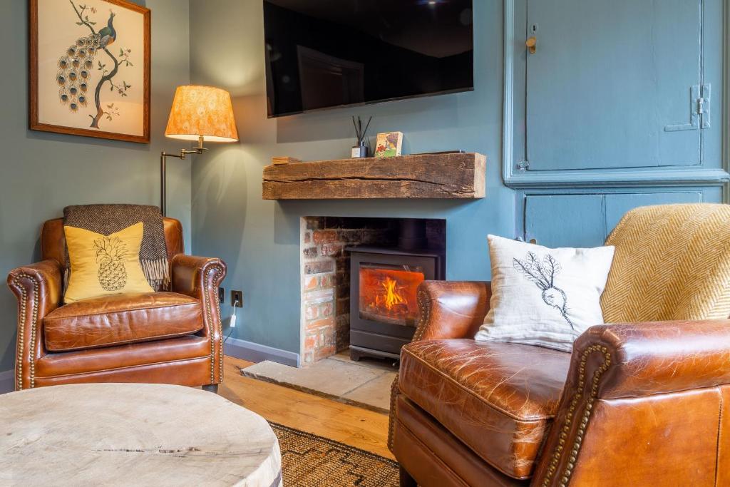 a living room with two chairs and a fireplace at Tipple Cottage in Peasenhall