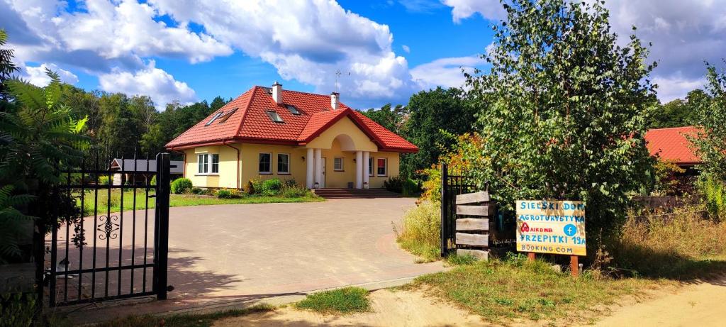 een huis met een rood dak voor een poort bij Sielski Dom in Nowe Miasto