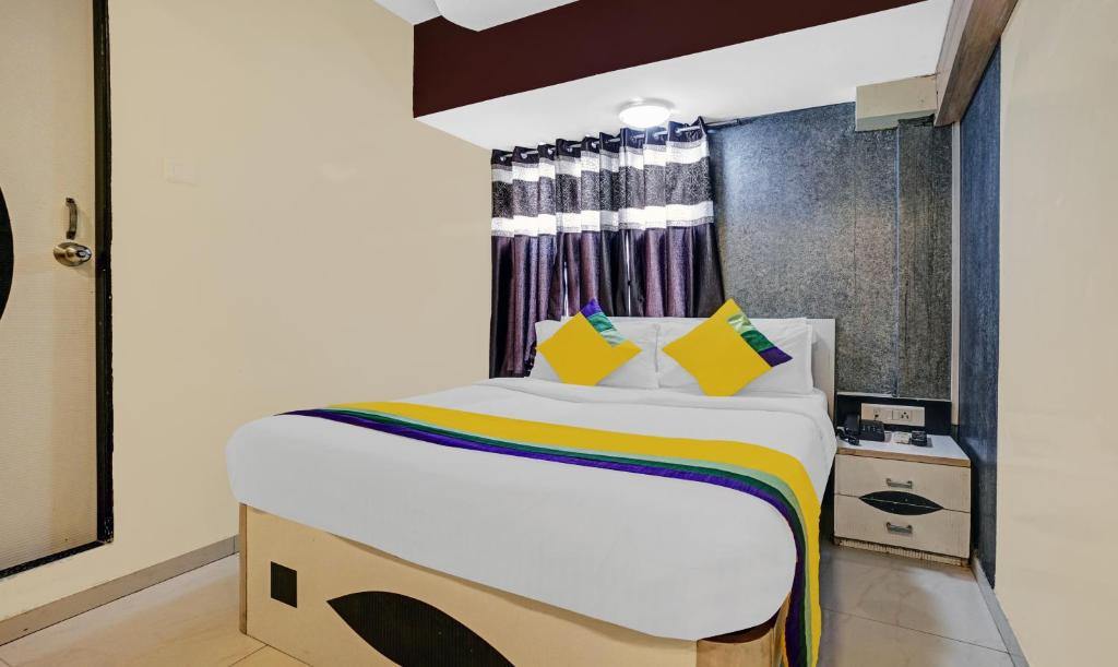 a bedroom with a large bed with yellow pillows at Amber Corp Inn, Near Nesco Exhibition Center in Mumbai