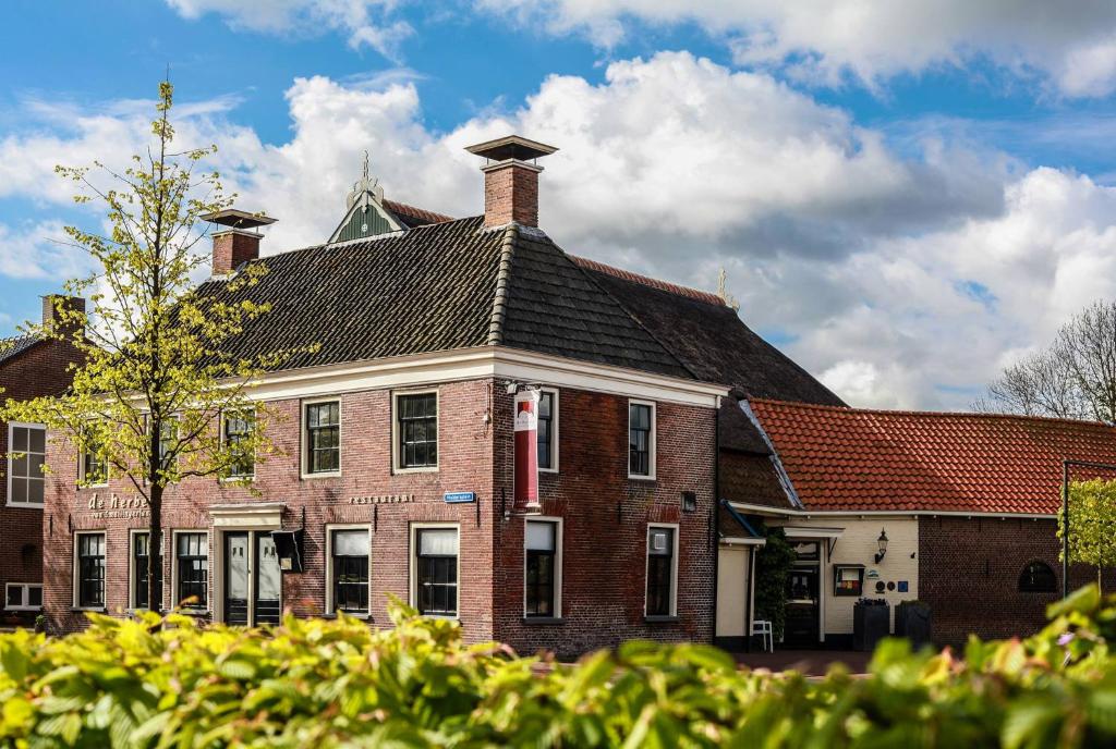 a large red brick house with a roof at Teades Plak bij De Herberg van Smallingerland in Rottevalle