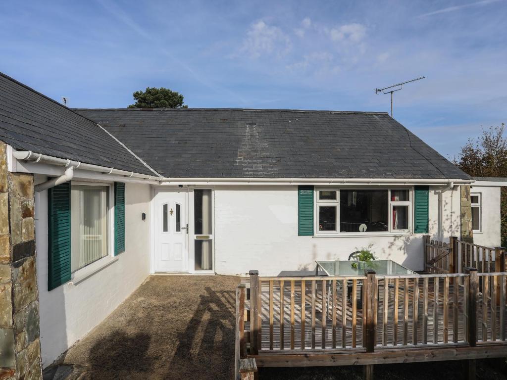a white house with a wooden deck at 14 Cae Pin in Pwllheli