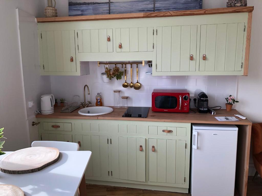 a kitchen with white cabinets and a red microwave at Juste au dessus de la Veules in Veules-les-Roses