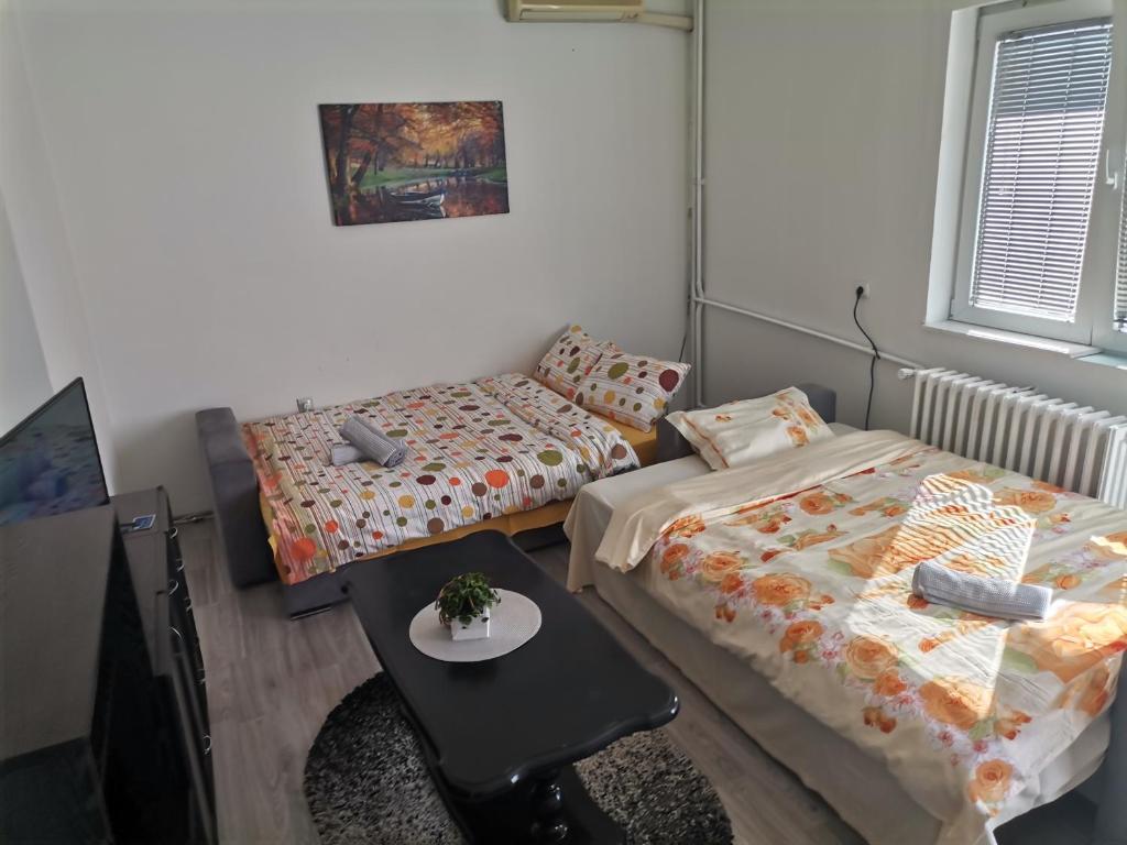 a room with two beds and a table and a couch at CALLA - Modern & Cozy Main Square Apartment in the City Shopping Center - PARKING SLOT with parking security in Skopje