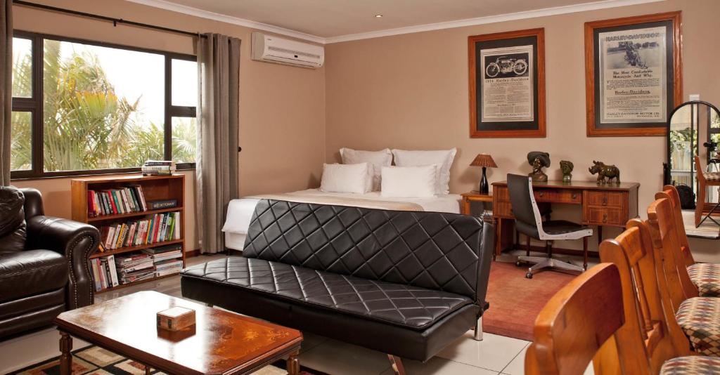a bedroom with a bed and a desk and a couch at Carrington Guest House in Durban