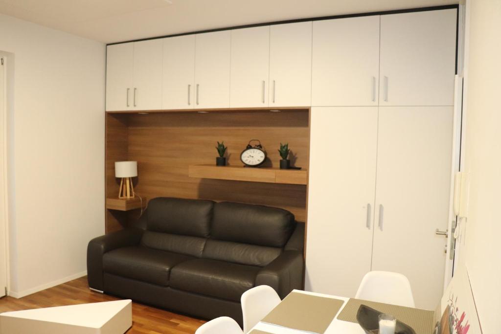 a living room with a black leather couch and white cabinets at Studio apartma Terme Ptuj in Ptuj