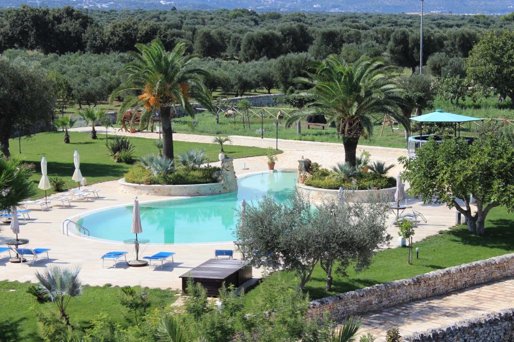 a swimming pool in a park with palm trees at Masseria Valente in Ostuni